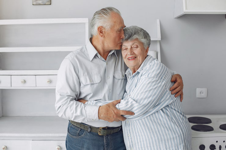 Elderly couple embracing at home.